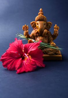 an elephant statue sitting on top of a table next to a flower