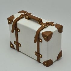 a white suitcase with brown handles and straps on the top is sitting in front of a gray background