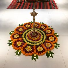 a large flower arrangement on the floor in front of a lit candle and other decorations