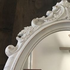 an ornate white mirror on a wooden floor