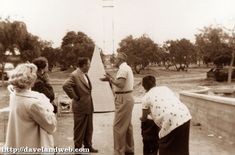 an old black and white photo of people standing in front of a cross