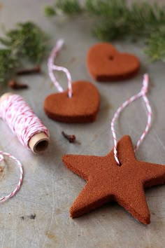 some brown and white ornaments on a table with twine, spools of thread and heart shaped cookies