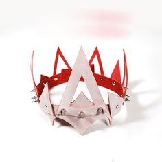 a red and white paper crown with spikes on it's sides, sitting in front of a white background