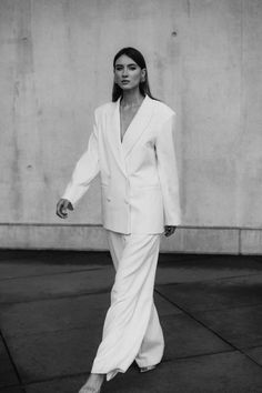 a woman in a white suit walking down the street