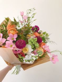 a bouquet of flowers is being held by someone's hand on a white background