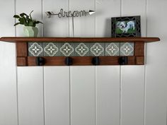 a wooden shelf with three hooks on it and an arrow sign hanging above the top