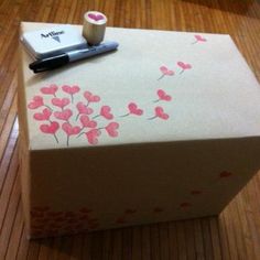 a white box with pink flowers on it and a pen sitting on top of it