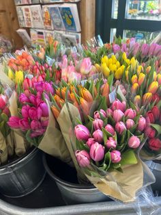 colorful tulips are in buckets on display at a flower shop for sale