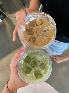 two people holding up cups with ice cubes in them