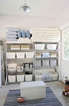 a room filled with lots of white baskets and storage containers on metal shelving units