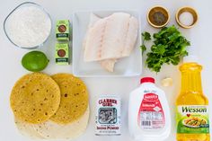 the ingredients to make this dish are laid out on a white counter top, including tortilla shells, limes, and seasoning