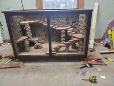 a display case made out of rocks in a room with tools and construction materials on the floor