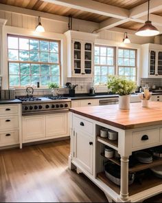 a large kitchen with white cabinets and wooden counter tops, an island in the middle