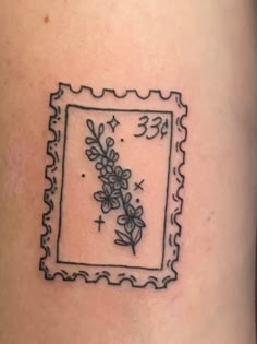 a small tattoo on the side of a woman's leg that has a frame with flowers in it