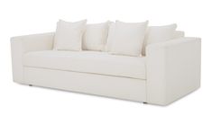 a white couch with four pillows on it's back and one arm facing the camera