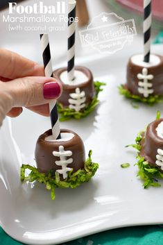 chocolate football marshmallow pops on a white plate with black and white striped straws