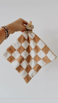 a hand holding a brown and white checkered towel