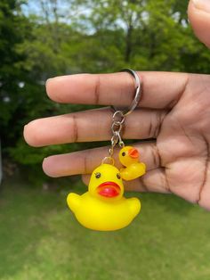 a hand holding a yellow rubber ducky keychain