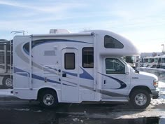 an rv parked in the parking lot with snow on the ground and cars behind it