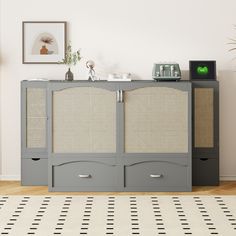 a grey cabinet with two drawers and some pictures on the wall behind it in a living room