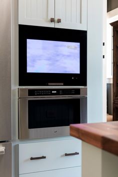 the microwave is built into the wall and has a flat screen tv on top of it