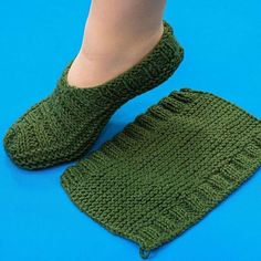 a child's feet in green knitted slippers on a blue surface with the bottom part of their leg visible