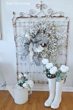 two white boots with flowers in them sitting next to a wall hanging on the wall