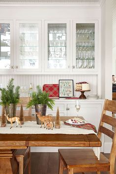 an image of a dining room setting with christmas decorations on the table and two cats sitting at the table