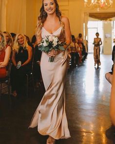 a woman is walking down the aisle with flowers in her hand