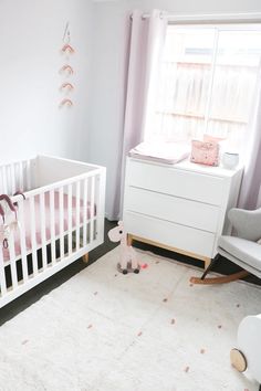 a baby's room with a crib, rocking chair and dresser in it