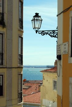 a street light hanging from the side of a building next to a body of water