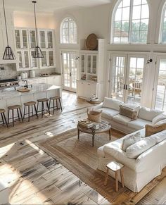 a living room filled with furniture and lots of windows in the middle of an open floor plan