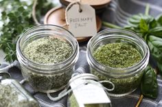 three jars filled with different types of herbs on top of a table next to spices