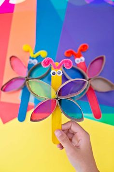 a hand holding up a colorful paper flower