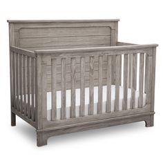 a wooden baby crib with white sheets on the bottom and sides, in front of a white background