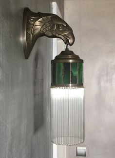 a wall mounted light with a green glass shade hanging from it's side in a room