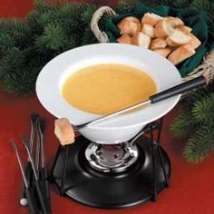 a bowl of soup and chopsticks on a red table with pine branches in the background