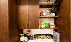 a small kitchen with wooden cabinets and white counter tops, filled with colorful dishes on shelves