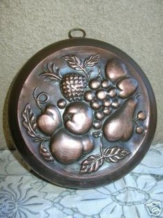 a metal plate with fruit and leaves on it