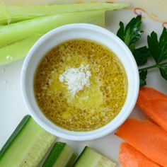 carrots and celery on a white plate next to a cup of liquid