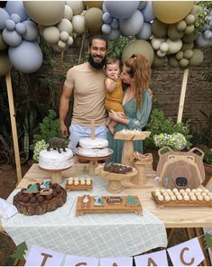 a man, woman and child standing in front of a table with desserts