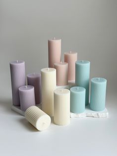 many different colored candles sitting next to each other on a white surface with one candle in the middle