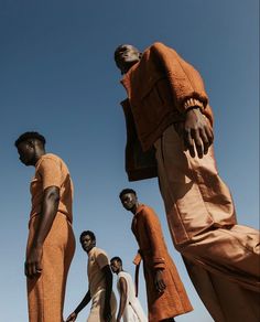 four men in orange clothing standing next to each other with their hands on their hipss