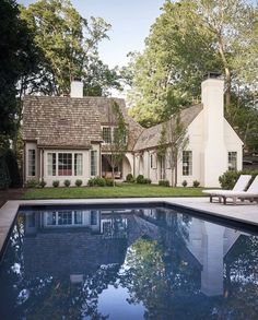 a house with a pool in front of it and lawn chairs around the pool area