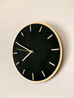 a black and gold clock on the wall with white numbers is shown in this image