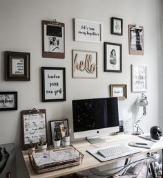 a desk with a computer on top of it in front of a wall full of pictures