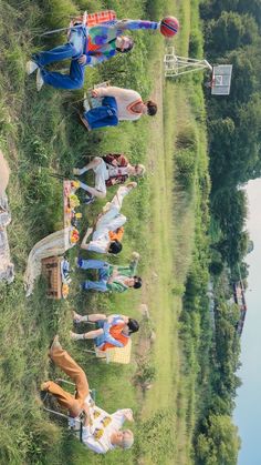 several people are laying on the grass near water