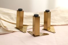 three brass candlesticks sitting on top of a bed