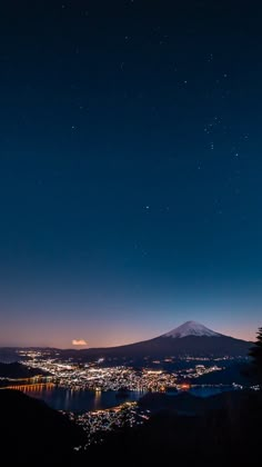 the night sky is lit up over a city and mountain range with stars in the sky