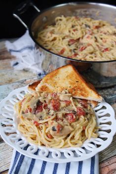 a white plate topped with pasta next to a skillet filled with cheese and sauce